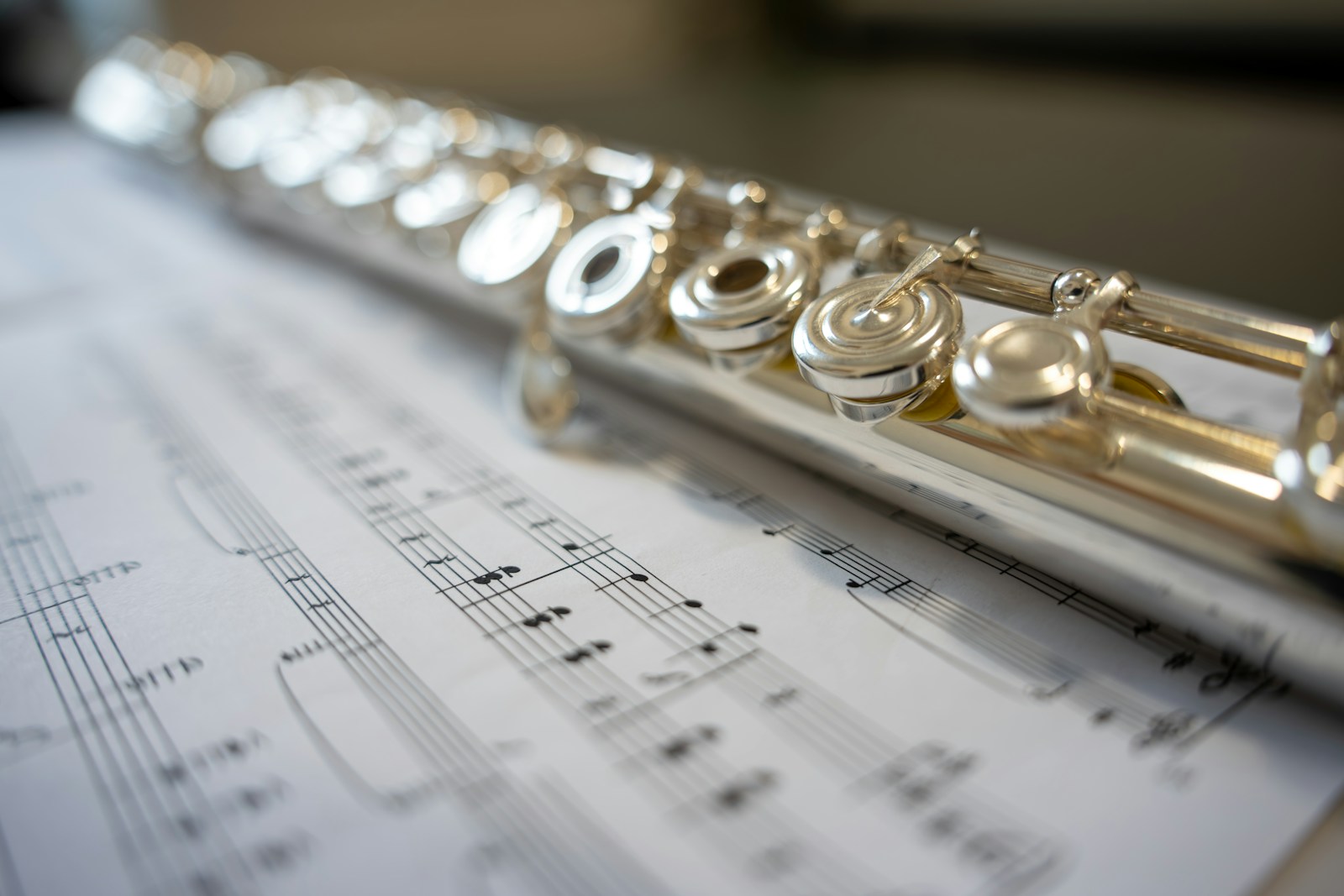 A silver flute rests on sheet music